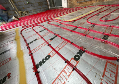 Coiled red underfloor heating pipe installed on top of foil backed insulation board