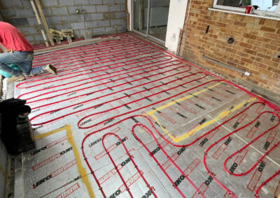 Coiled red underfloor heating pipe installed on top of foil backed insulation board