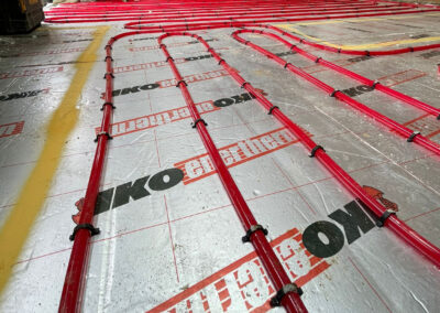 Coiled red underfloor heating pipe installed on top of foil backed insulation board